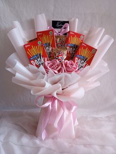 a bouquet of pink roses and candy wrapped in white paper