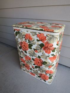 an orange and white flowered box sitting on the side of a house