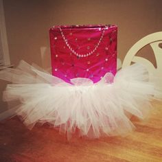 a red gift bag with white tutu and pearls on it sitting on a table