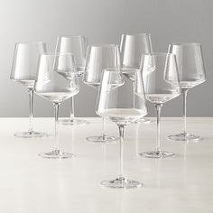 a group of wine glasses sitting on top of a white table next to each other