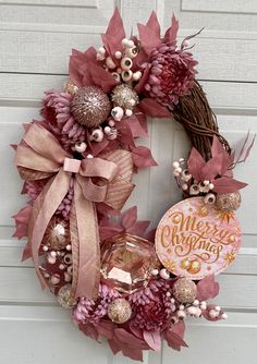 a wreath with pink and gold decorations hanging on a door