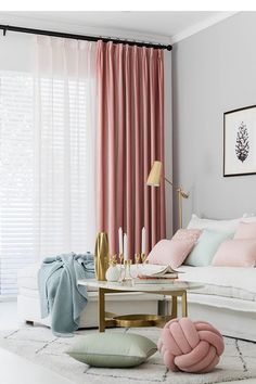 a living room with pink curtains and pillows on the floor, along with other furniture