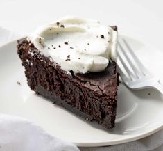 a piece of chocolate cake with whipped cream on top is sitting on a white plate