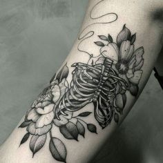 a black and white photo of a skeleton with flowers on it's arm,