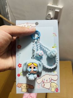 a hand holding a keychain with some cartoon characters on it