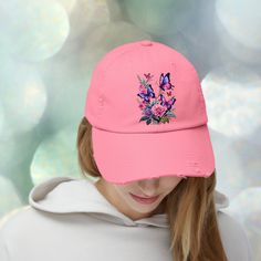 a woman wearing a pink baseball cap with butterflies on the front and flowers on the back