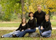 a group of people sitting on top of a rock in front of some trees and grass