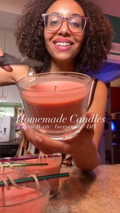 a woman in glasses is holding a cup with some liquid inside it and smiling at the camera