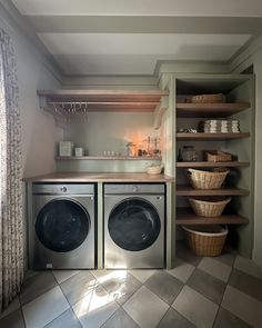 a washer and dryer in a small room with open shelving on the wall