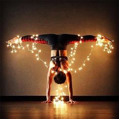 a woman doing a handstand with lights around her