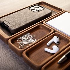 a wooden tray with ear buds, headphones and an iphone