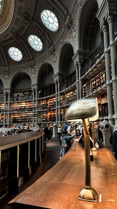 a large library filled with lots of books and people sitting at the tables in front of them