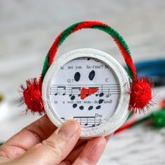 someone is holding up a christmas ornament with music notes and red pom - poms