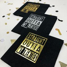 three black and gold napkins with confetti on the table next to them