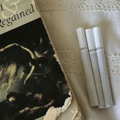 an old book and three white straws on a bed