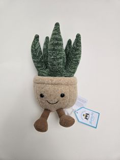 a small stuffed cactus with a green plant on it's head and a tag in front of it