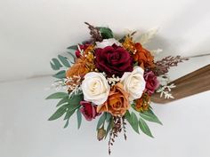 a bridal bouquet with red, white and orange flowers on it's side