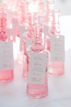 pink glass bottles with labels on them are lined up in the shape of small flasks