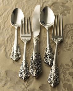 five silverware forks and spoons on a tablecloth with an intricate design in the middle