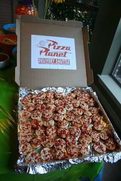 a box filled with mini pizzas sitting on top of a green table next to a window