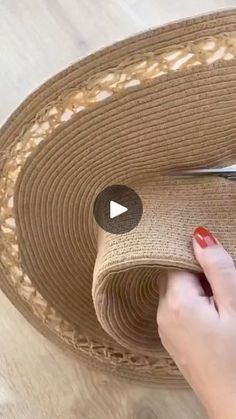 a woman is cutting up the edge of a straw hat with scissors and yarn on it