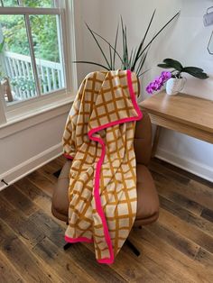 a chair with a blanket on top of it next to a table and potted plant