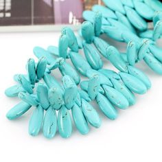 turquoise colored beads are arranged on a white surface