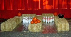 some hay with bowling pins and oranges on it