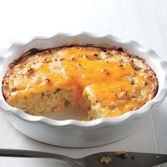 a casserole dish with cheese on top and a serving spoon next to it