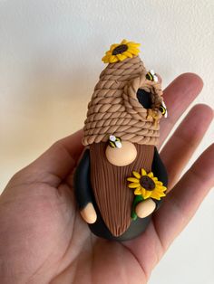 a hand holding a small figurine with sunflowers on it's head