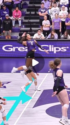 a group of women playing volleyball in front of a crowd on a purple and white court