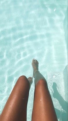 a woman's legs in the water near a swimming pool with clear blue water