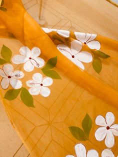 an orange and white floral print fabric with green leaves on the top, in front of a tile floor