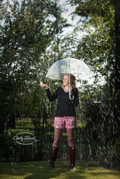 a woman standing under an umbrella in the rain with her hands out to catch it