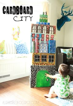 a toddler playing in front of a cardboard city