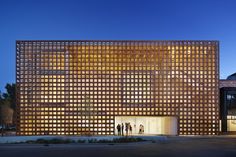 people are standing in front of a building that is lit up at night with the lights on