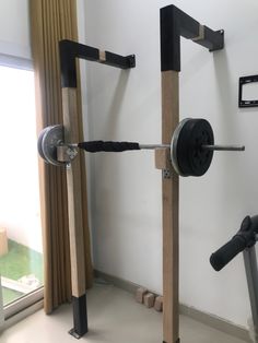 the gym equipment is made out of wood and has metal bars attached to it, along with two dumbbells