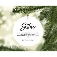 a christmas ornament hanging from a tree with the words sisters and love written on it