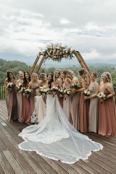 a bride and her bridal party at the top of a wooden deck with an arch