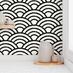 a white shelf sitting next to a wall covered in black and white art deco tiles