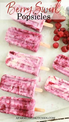 berry swirl popsicles on a cutting board with berries