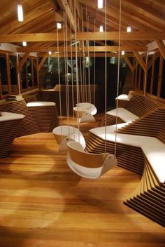 a room filled with lots of wooden furniture and hanging chairs in it's ceiling