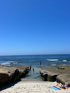 people are relaxing on the beach by the water