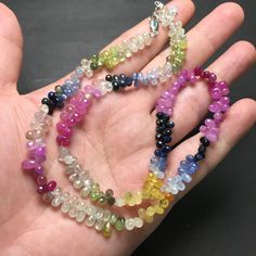 a person's hand holding several different colored beads