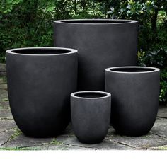 three cement pots sitting on top of a stone floor