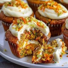 carrot cupcakes with white frosting and sprinkles on a plate