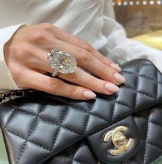 a woman's hand holding a black chanel bag with a diamond ring on it