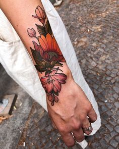 a person with a flower tattoo on their left arm and the other hand is holding an object