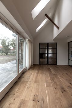 an empty room with wooden floors and large windows