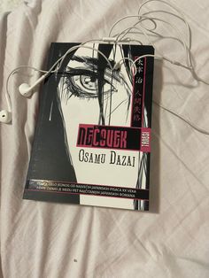 a book with ear buds attached to it laying on a bed